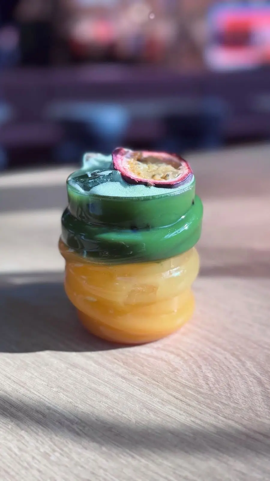 Passionsfrucht Matcha im gewellten Glas, obenauf eine halbe Passionsfrucht